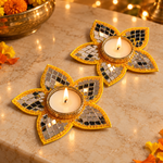 Yellow five-petal mirror tea light holder pair on a festive marble setting
