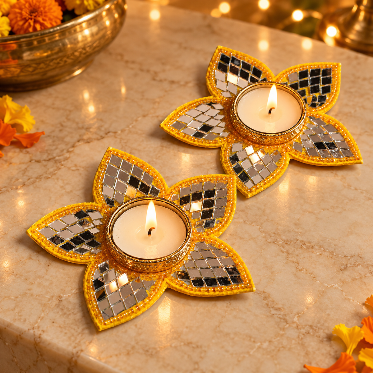 Yellow five-petal mirror tea light holder pair on a festive marble setting